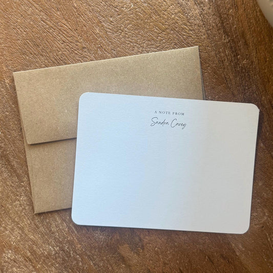 White card with text and brown envelope on a wooden surface