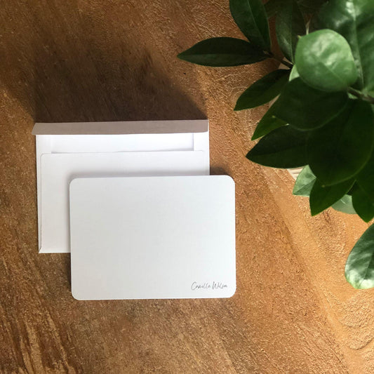 White customized greeting card with a plant on a wooden surface