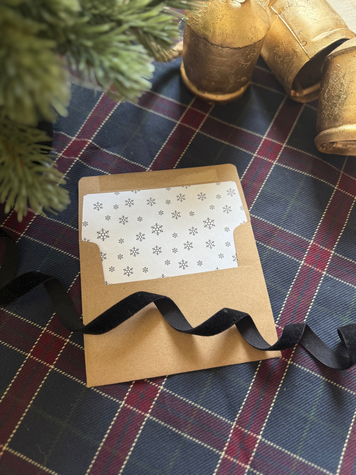 Kraft paper envelope with a decorative ribbon on a plaid fabric background