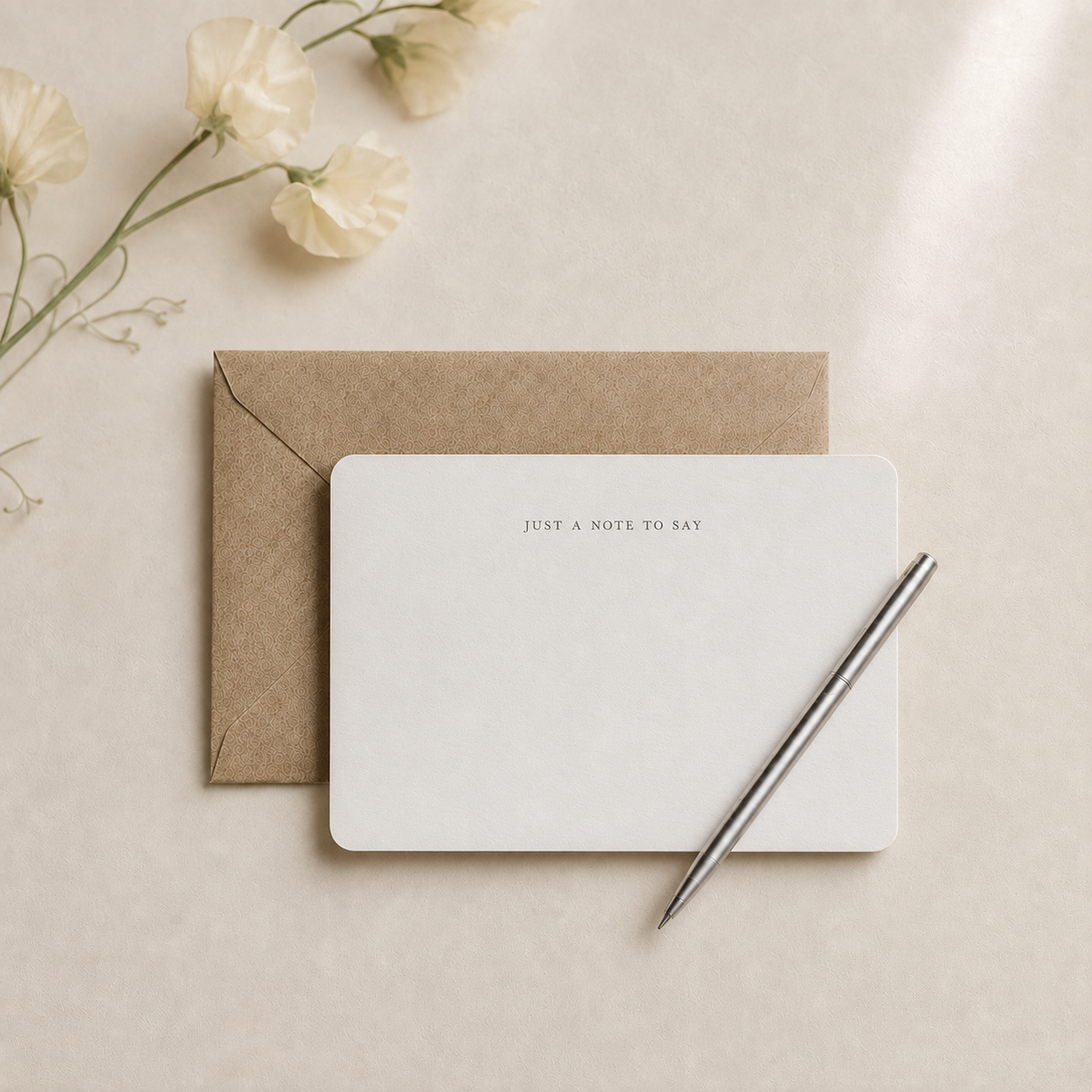 Rounded personalized notecard with kraft envelope and silver pen on ivory linen